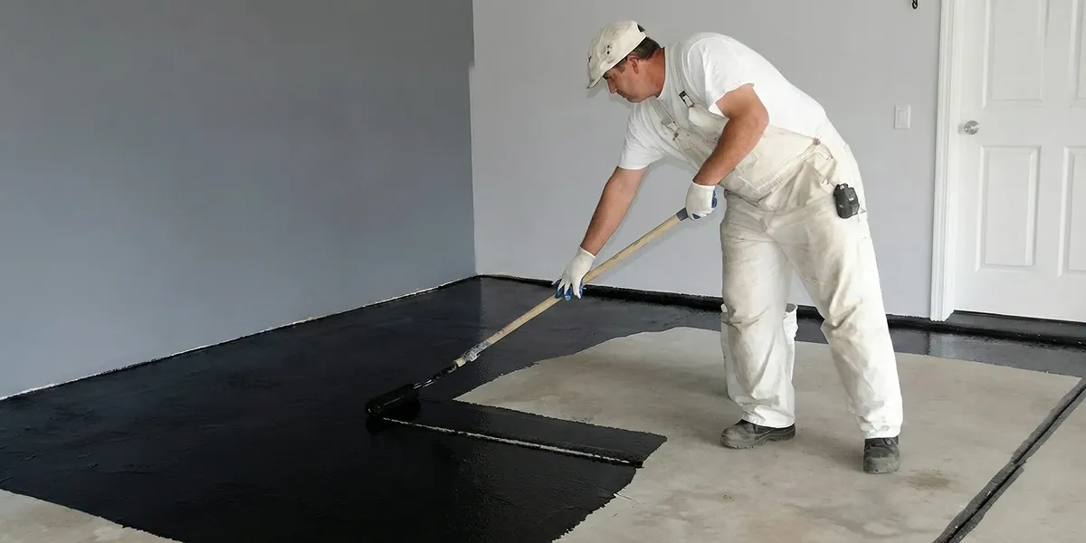 basement waterproofing professional applying waterproof coating to protect a basement floor in Tacoma, WA